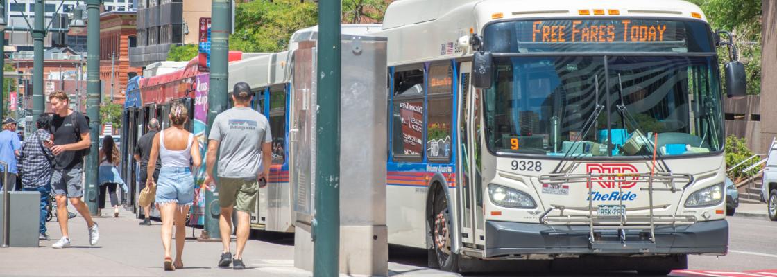 People walking down a sidewalk next to a bus on a city street.